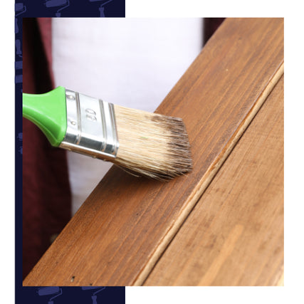 Exterior StainsA hand paints a wooden surface with a brush featuring green handle, applying light brown stain. The scene conveys craftsmanship and care.